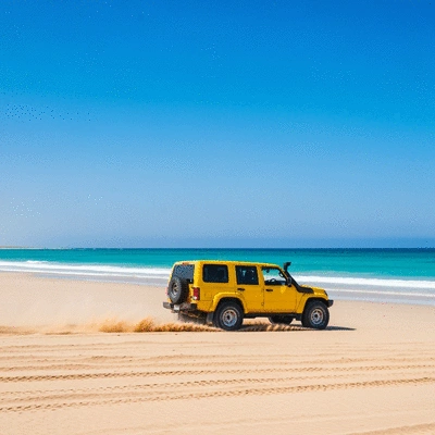 4WD vehicle driving through a sandy beach with ocean in background